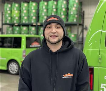 Male with hat standing in front of SERVPRO vehicles 